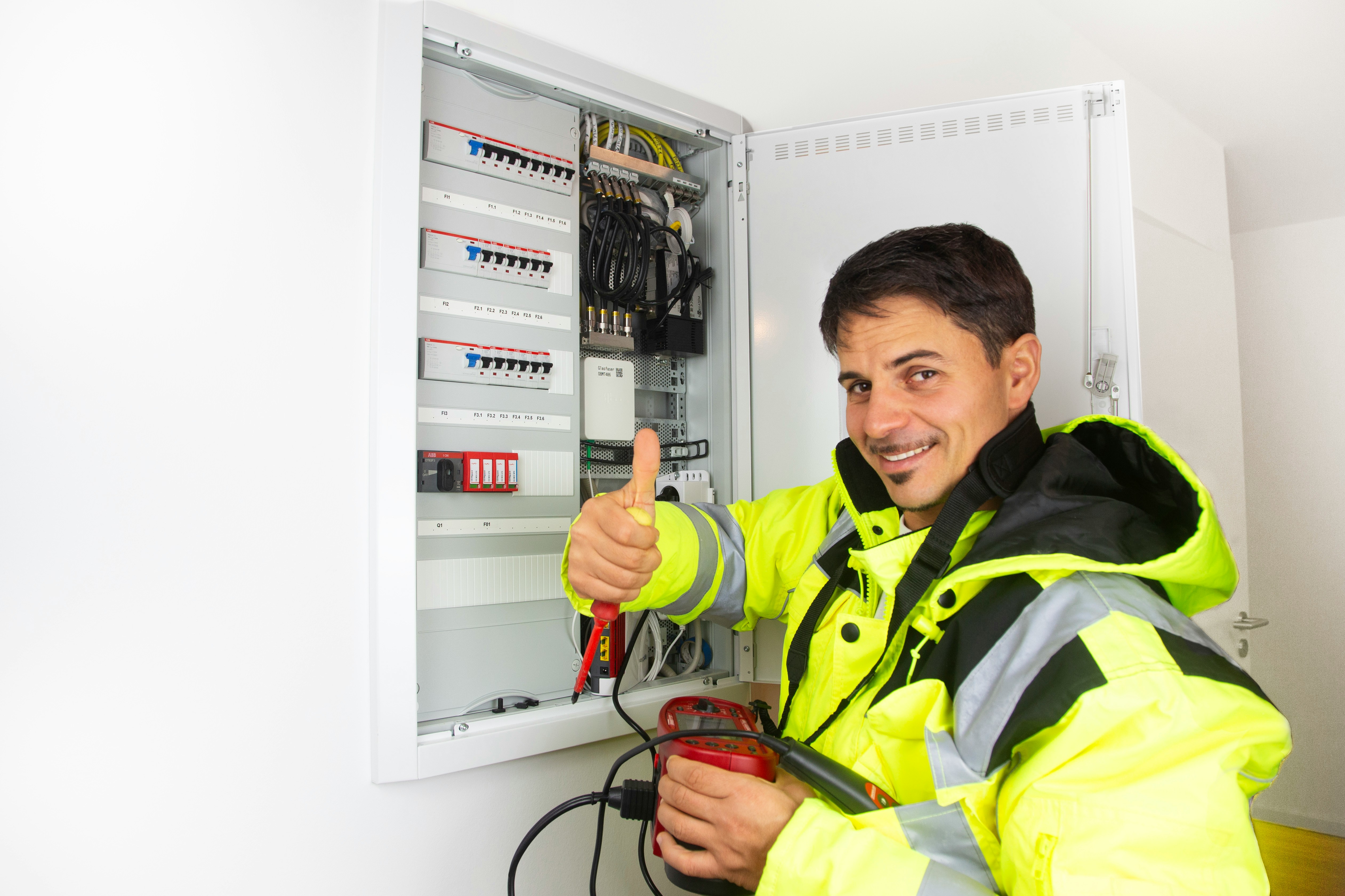 Engineer in hi-vis giving a thumbs up at a consumer unit